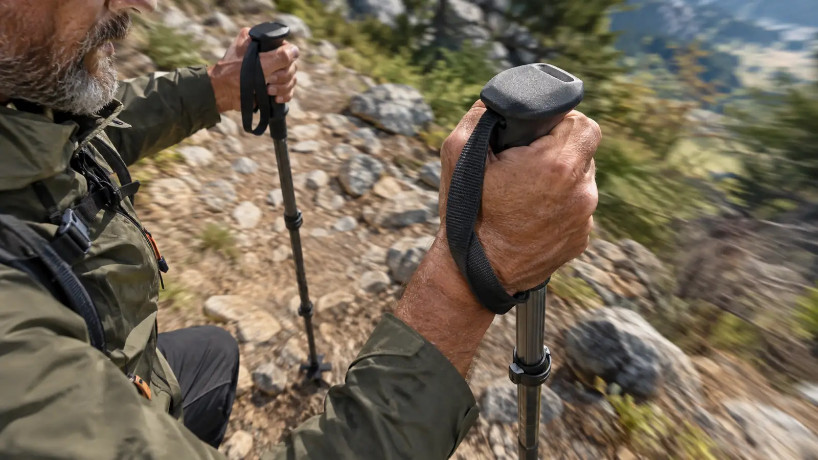 A hand gripping a trekking pole handle while the basket rests on a rocky trail