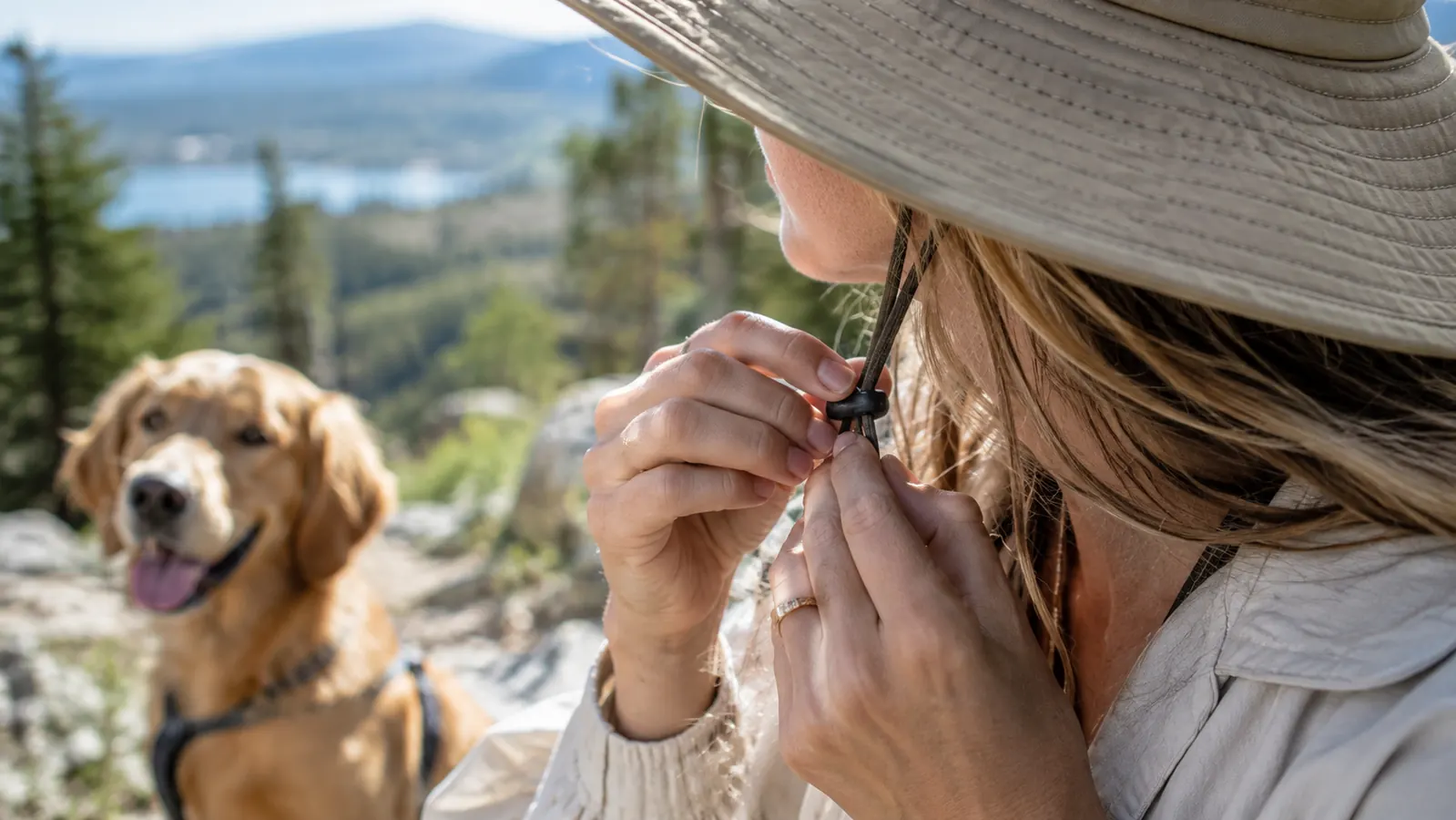 A person adjusting the chin strap of a wide brim sun hat before a walk
